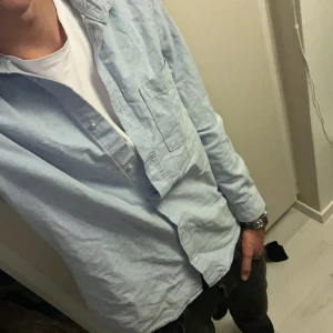 Ljusblå bomullsskjorta med knappar - Skriv vid funderingar 