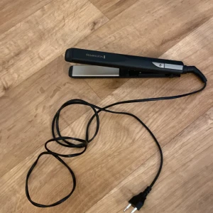 Remington plattång svart och silver - En stilren plattång från Remington i svart och silver med sladd och europeisk kontakt. Plattorna är släta och av metall, perfekt för att fixa rakt hår eller skapa lockar. Enkel att använda med on/off-knapp och smidig design.