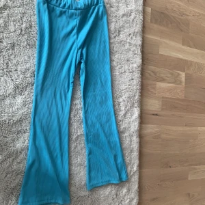 Turkosa ribbade bootcut byxor - Säljer ett par turkosa ribbade byxor med bootcut-modell. Byxorna har hög midja och är gjorda i ett stretchigt, mjukt material som känns skönt mot huden. Perfekta för dig som gillar färg och vill sticka ut lite extra.