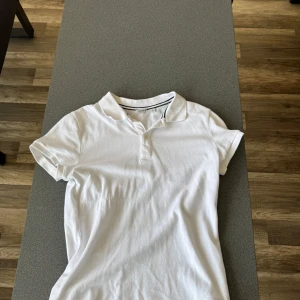 Vit pikétröja från Björn Borg - Klassisk vit pikétröja från Björn Borg med korta ärmar och krage med två knappar. Tröjan har en diskret logotyp nertill och är gjord i mjuk bomull, perfekt för en clean och sportig look. Passar lika bra till jeans som till shorts.