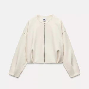 Beige/vit croppad jacka med dragkedja från Zara - Säljer en stilren beige/vit  jacka från Zara med rak passform och croppad längd. Jackan har rund halsringning och stängs med en dragkedja framtill. Perfekt för lager-på-lager och enkel att matcha.