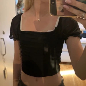 Svart croppad topp från H&M Divided - Säljer en svart croppad topp från H&M Divided med korta puffärmar i mesh och rynkade detaljer framtill. Toppen har en fyrkantig urringning. Perfekt för att lyfta vilken outfit som helst! Skriv om frågor finns!💕💕