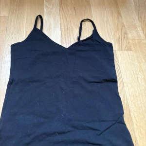 Svart linnetopp från 157 - Svart enkel linnetopp från 157 med smala axelband och v-ringad halsringning. Använt fåtal gånger. 