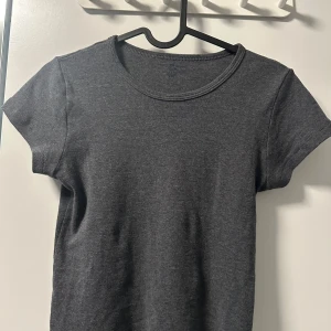 Mörkgrå basic t-shirt  - En enkel och stilren mörkgrå t-shirt från Brandy Melville. T-shirten har rund halsringning och korta ärmar, tillverkad i 100% bomull. Perfekt till jeans eller kjol för en avslappnad look. Aldrig använt. 🩶