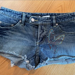 Lågmidjade jeansshorts - Mörkblå jeansshorts med fjärilsmönster på både fram- och baksidan. Superfina till sommaren och passar till flera evenemang- skolan, middag, fest etc. Lite små i storleken💕
