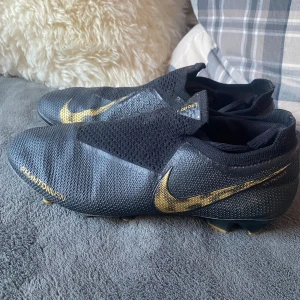 Nike Phantom Vision fotbollsskor svart/guld - Säljer ett par Nike Phantom vsn. Väldigt bra skick använda 4-5 träningar. Går inte att köpa längre de är en modell från 2017. Strl 42. Endast 499kr