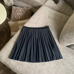 Marinblå plisserad kjol från H&M - Säljer en marinblå plisserad minikjol från H&M. Kjolen är i nyskick med etikett kvar. 