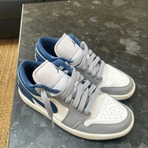Nike Air Jordan 1 Low i grått och blått - Säljer ett par Nike Air Jordan 1 Low French blue💙🤍🩶Fint skick, knappt använda. Jordan kartongen ingår! Rengörs innan de skickas. Hör av er vid fler frågor!