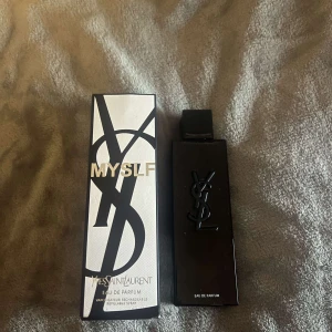 Yves Saint Laurent MYSLF Eau de Parfum - Säljer en elegant parfym från Yves Saint Laurent, MYSLF Eau de Parfum. Flaskan är svart och rektangulär med YSL-loggan i relief. Kommer i originalförpackning med stilren svartvit design och guldtext.