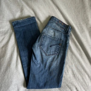 Dondup jeans - Snygga blåa Dondup jeans, tillverkade i Italien. Klassisk femficksmodell med dragkedja och knapp framtill. Jeansen har raka ben och diskreta slitningar framtill för en cool look.