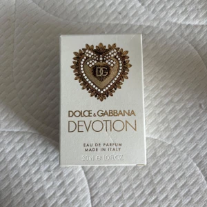 Dolce & Gabbana Devotion EdP 30 ml - Helt ny Dolce & Gabbana Devotion parfym, endast sprejad nån gång för att känna doften. Det är en lyxig parfym i en elegant glasflaska med guldfärgat hjärtemblem och lock. Doften är exklusiv och flaskan rymmer 30 ml. Perfekt för dig som vill ha något unikt och stilrent i parfymhyllan. Köpt på kicks för 995kr