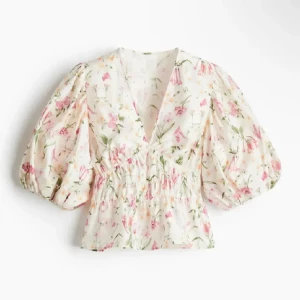 Blommig blus med puffärmar - Söt blommig blus i vitt med rosa och gröna detaljer. Blusen har v-ringning, voluminösa puffärmar och smockad midja som ger en feminin siluett. Perfekt för vår och sommar! Slutsåld överallt och helt ny med lappar kvar, därav priset. Priset går att diskuteras ❣️