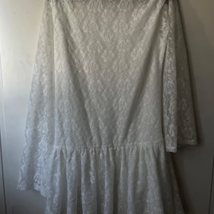 Vit spetsklänning från ASOS DESIGN - Säljer en vit kortklänning från ASOS DESIGN med långärmade ärmar och vackert blommigt spetsmönster. Klänningen har en volang nedtill och är perfekt för somriga tillfällen. Skulle ha till student men hittade en annan. Aldrig använd 