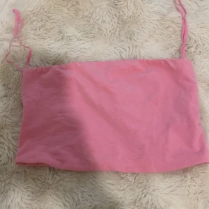 Rosa tubtopp från Stradivarius - Säljer en söt rosa tubtopp från Stradivarius. Perfekt för varma dagar och enkel att matcha med jeans eller kjol. Mjuk och skön känsla mot huden.