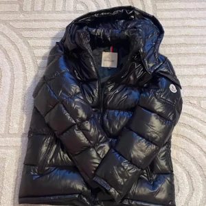 Svart dunjacka från Moncler - Säljer en svart dunjacka från Moncler med huva. Jackan har klassisk pufferdesign. Perfekt för kyliga dagar och riktigt snygg till vintern nfc Scan funkar också har kvar tag.