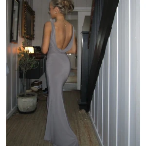 Lång grå klänning med öppen rygg - Säljer denna eleganta och snygga långklänning i grått. Den är helt oanvänd och säljer då jag inte får användning för den. Den heter flora maxi dress och är från design by si🫶🏼🩷🩷