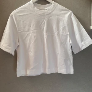 Vit boxy t-shirt från Gina Tricot - Säljer en basic vit boxy t-shirt från Gina Tricot i storlek XXS. T-shirten har trekvarts ärmar, rund halsringning och en rak, lite croppad passform. Perfekt till sommaren och enkel att matcha med allt. Tröjan är aldrig använd och har prislapp kvar. Hoppas någon kan få användning av toppen. Nypris-199kr