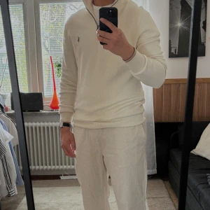 Vit halvzip-tröja från Polo Ralph Lauren - Säljer en stilren vit halvzip-tröja från Polo Ralph Lauren i mjuk pima-bomull. Tröjan har lång ärm, ribbade muddar och en liten broderad logga på bröstet. Perfekt för en clean och klassisk look.