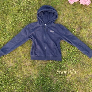 Mörkblå hoodie från Fila - Säljer en mörkblå hoodie från Fila med dragkedja framtill och huva. Tröjan har två fickor och ribbade muddar vid ärmslut och nederkant.