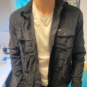 Svart overshirt från RVCA - Säljer en svart overshirt från RVCA i regular fit. Overshirten har två bröstfickor med knappar och klassisk krage. Perfekt att bära öppen över en t-shirt eller stängd för en mer stilren look.