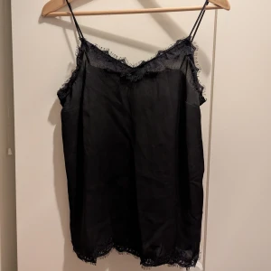 Svart linne med spetsdetaljer - Snyggt svart linne med tunna axelband och spetsdetaljer längs kanterna.🙂 Säljer då den är för liten för mig.