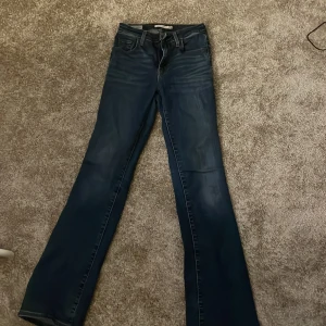 Blå bootcut jeans från Levi's - Snygga blå Levi's 725 high rise bootcut jeans. De har en klassisk femficksdesign och en bekväm hög midja. Perfekta för en avslappnad stil med en touch av retro.