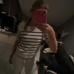 Vit och marinblå randig topp från Zara - Säljer en stilren vit topp med marinblå ränder från Zara. Toppen har korta ärmar och en klassisk rund halsringning. Perfekt för en avslappnad och trendig look. Passar bra till både jeans och kjol. 🖤