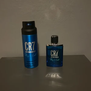 CR7 Play it Cool Parfym och Body Spray - Säljer en CR7 Play it Cool parfym och body spray från Cristiano Ronaldo. Parfymen kommer i en stilren blå flaska med silverdetaljer och har en fräsch doft. Body sprayen matchar med samma blå design och är perfekt för en uppfriskande känsla. Perfekt för den som vill känna sig fräsch och självsäker. Nästan aldrig använd.