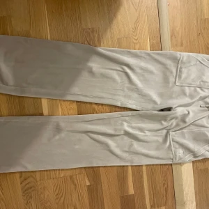 Beige mjukisbyxor från Juicy Couture och tröja till ett sett  - Säljer ett par bekväma beige mjukisbyxor från Juicy Couture. Byxorna har en avslappnad passform med fickor baktill och en mjuk känsla. Perfekta för en chill dag hemma eller en avslappnad utflykt.