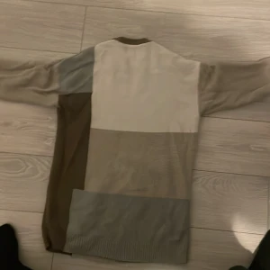 Beige och brun stickad tröja från Zara - Säljer en snygg stickad tröja från Zara i olika nyanser av beige och brun. Tröjan har ett blockmönster och långa ärmar, perfekt för kyligare dagar. Den är tillverkad i Turkiet och har en bekväm passform.