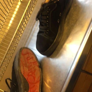 Svarta sneakers från Christian Louboutin - Snygga svarta sneakers från Christian Louboutin med den ikoniska röda sulan. Skorna har snörning och en stilren design som passar perfekt för en trendig look.