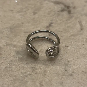 Silverfärgade ringar från Cheap Monday - Snygg och stilren silverfärgade ringar från Cheap Monday. Unik design med en öppen front och dubbla band som ger en modern touch. Perfekt för att komplettera din outfit med en minimalistisk stil. Endast 1 ring använd, den andra oanvänd!💖