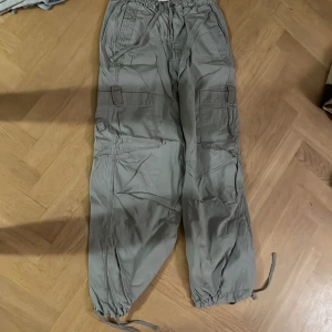 Gråa  cargopants från FB Sister - Snygga gröna cargopants från FB Sister med flera praktiska fickor och justerbara benslut. Perfekta för en avslappnad stil med en touch av funktionalitet. Byxorna har en loose passform och är tillverkade i ett bekvämt material. Köpta på newyorker