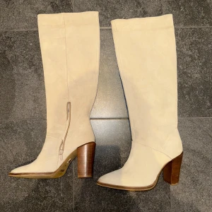 Beige stövlar från Bronx - Snygga beige stövlar från Bronx med spetsig tå och klack. Tillverkade i mocka med en stilren design som passar perfekt för höst och vår, utgång och vardag. Dessa stövlar har en dragkedja på insidan för enkel på- och avtagning. Köptes för 2400kr. Nypris på Bronx stövlar ligger mellan 1800kr-3000kr, använda endast två gånger sen köp! Denna exakta modell går inte längre att köpa heller. Pris kan sänkas vid snabb affär!
