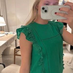 Grön ärmlös klänning med spetsdetaljer - Snygg grön blus från Zadig & Voltaire med spetsdetaljer på ärmarna. Den är ärmlös och har en elegant design som passar perfekt för sommarens tillställningar.