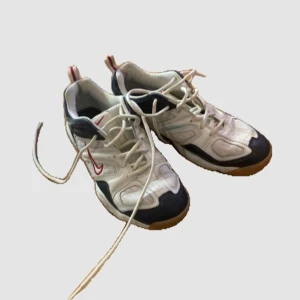 Vintage Nike skor - Snygga vita sneakers med svarta och röda detaljer från Nike. Skorna har en klassisk design med snörning och en bekväm sula. Perfekta för en sportig look.