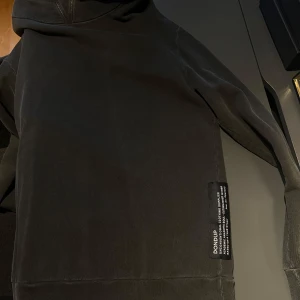 Svart hoodie från Dondup - Säljer en stilren svart hoodie från Dondup. Tröjan har en klassisk design med långa ärmar och en bekväm huva. Perfekt för en avslappnad look.