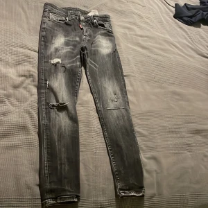 Svarta jeans från Dsquared2 - Snygga svarta jeans från Dsquared2 med slitna detaljer och en cool, tvättad look. De har en knappgylf och klassisk femficksdesign. Perfekta för en trendig stil. Lägg pris bud ifall intresserad👀