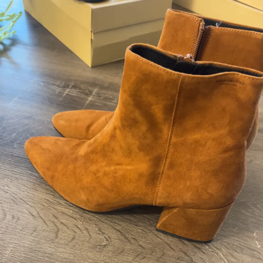 Snygga bruna boots i mocka med dragkedja på sidan och en bekväm klack. De har en spetsig tå som ger en elegant touch. Perfekta för att lyfta din outfit med stil. Ordinarie pris 1500. Kengät.