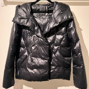Svart dunjacka med huva - Snygg svart dunjacka med huva och dragkedja. Jackan har en glansig yta. Från Everest i storlek 34. Knappt använd. Priset går att diskutera. Köparen står för frakten 🩷 pris går att diskutera. 