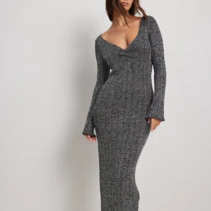 Glittrig långklänning från NA-KD - Snygg glittrig långklänning från NA-KD i svart och silver. Klänningen har en v-ringad design och långa ärmar, perfekt för en kväll ute. 