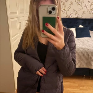 Lila dunjacka från Uniqlo - Säljer min uniqlo jacka. Färg lila och storlek xs. Den har några defekter på armen och på höger sidan av jackan som ni kan se på sista bilderna. Inget jag märker av och fläckarna smälter in ganska bra. Köpt för ca 800kr och är inte använd så jättemycket men priset är pga fläckarna