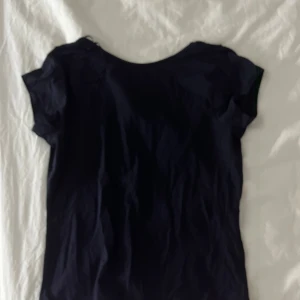 Svart kortärmad topp - Säljer en stilren svart kortärmad topp med rund halsringning. Perfekt för en enkel och klassisk look. Toppen är i ett mjukt och bekvämt material.