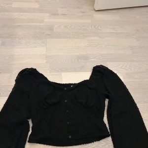 Svart blus med puffärm  - Svart blus från new yorker med långa puffärmar och små prickiga detaljer i tyget.