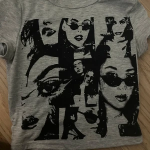 Grå t-shirt med svart grafiskt tryck - Snygg grå t-shirt med ett stort svart grafiskt tryck av ansikten och detaljer på framsidan. Rund hals och korta ärmar. Perfekt för dig som gillar coola och unika motiv. Materialet känns mjukt och bekvämt mot huden. Storlek xs. Köptes på Plick 