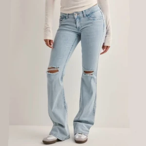 Ljusblå bootcut jeans med slitningar - De trendiga ljusblå jeansen från Nelly med hål på knäna som kostar 699 nypris. De är bootcut och Low waist i Storlek 36 (men uppsydda 2-3 cm) och i riktigt bra skick. 