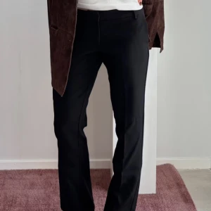 Lågmidjade svarta kostymbyxor med raka ben - Säljer ett par svarta kostymbyxor med raka ben och klassisk passform. Byxorna har hällor för bälte, diskreta bakfickor och stängs med dragkedja, knapp och hake. Dem har en låg midja, storlek 34/XS och är i ett mycket bra skick!💞