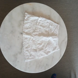 Vit broderad kortkjol från Escape - Supersöt vit kortkjol från Escape i storlek S. Kjolen har broderade detaljer med små hålmönster och en lätt volangkant. Perfekt för varma dagar och ger en fräsch och somrig vibe. Passformen är normal och materialet känns mjukt och luftigt.