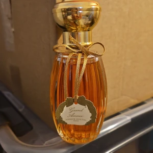 Grand Amour parfym Annick Goutal - Lyxig parfym Grand Amour från Annick Goutal i en elegant, räfflad glasflaska med guldlock och dekorativ guldfärgad rosett. Flaskan rymmer 100 ml Eau de Toilette och har en varm bärnstensfärgad vätska. Perfekt för dig som gillar klassiska och exklusiva dofter.