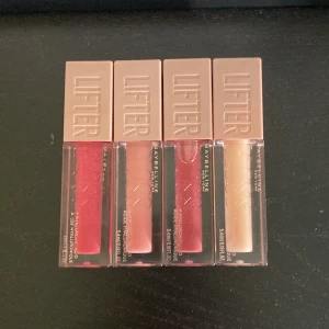 Maybelline Lifter Gloss 4-pack - Fyra Maybelline Lifter Gloss i nyanserna 24 Bubble Gum (rosa), 21 Gummy Bear (ljusrosa), 005 Petal (mauve/rosa) och 002 Ice (transparent/ljusbeige). Snygga gloss med hyaluronsyra för fylliga läppar, kommer i fyrkantiga genomskinliga förpackningar med beige lock.
